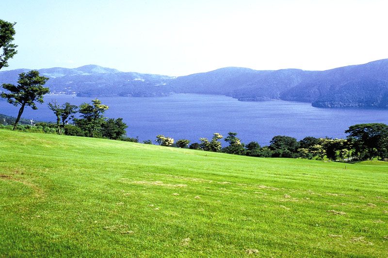 なだらかな傾斜の芝生の丘から望む芦ノ湖と対岸の山並み(公式サイトより)